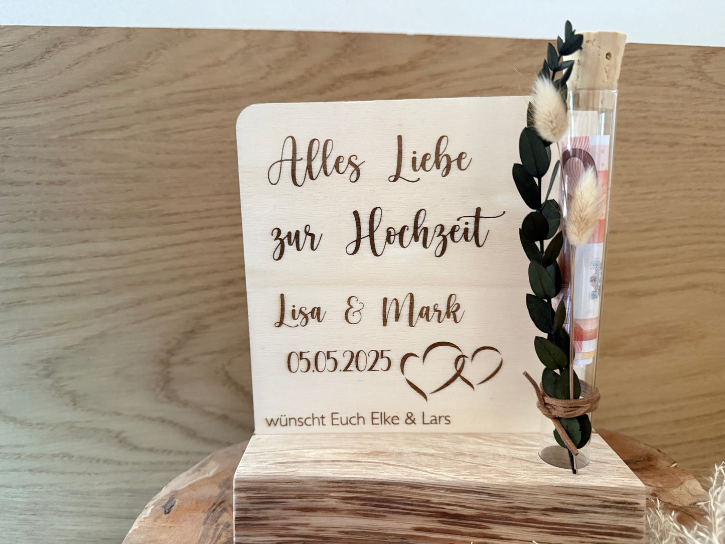 Geldgeschenk zur Hochzeit im Reagenzglas. Gravierte Holzplatte mit Alles Liebe zur Hochzeit. Namen des Brautpaares und das Hochzeitsdatum. Mit einer Halterung für das Reagenzglas, wo man das Geld einfügen kann.