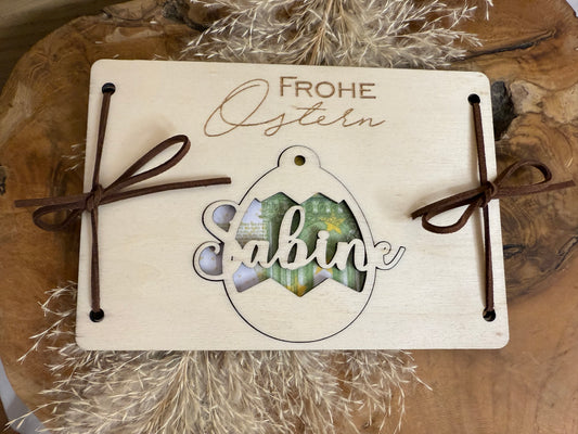 Geldgeschenkidee zu Ostern. Die handgemachte Holzkarte hat eine Größe von 16x11 cm. Auf der Karte wird Frohe Ostern graviert. Der Name wird auf einem Osterei eingraviert. Das Personalisierte Osterei dient dann zur dekoration.