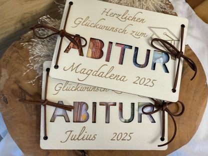 Geldgeschenk zum Abitur. Die Holzkarte wird mit Herzlichen Glückwunsch, den Namen und das Jahr graviert. Das Wort Abitur wird ausgeschnitten, damit man das Geld durchsieht.