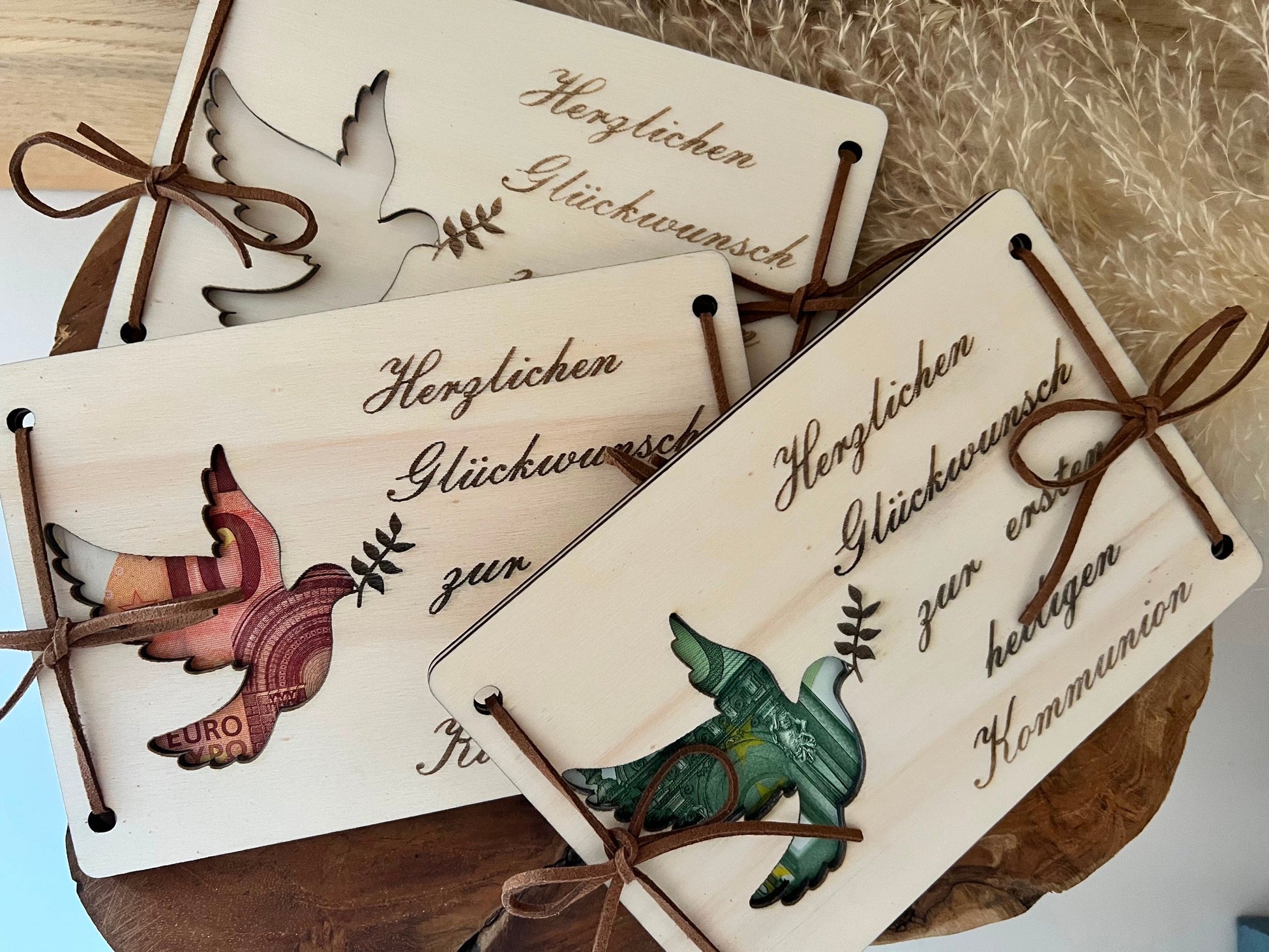 Geldgeschenk zur Kommunion. Gravierte Holzplatten mit der Aufschrift: Herzlichen Glückwunsch zur ersten heiligen Kommunion. Mit ausgeschnittenem Tauben Motiv. Legt man das Geld zwischen den 2 Holzplatten scheint es durch die Taube durch.