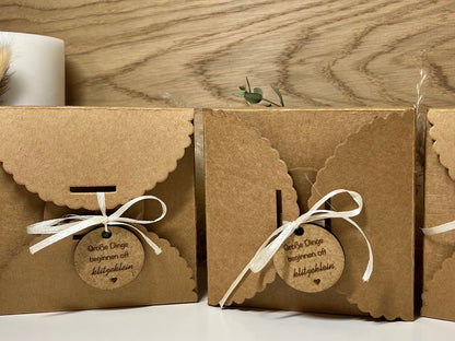 Geschenkverpackung mit der Aufschrift: Große Dinge beginnen oft klitzeklein. Darin befindet sich ein graviertes Holzherz mit der Überraschung du wirst Papa.