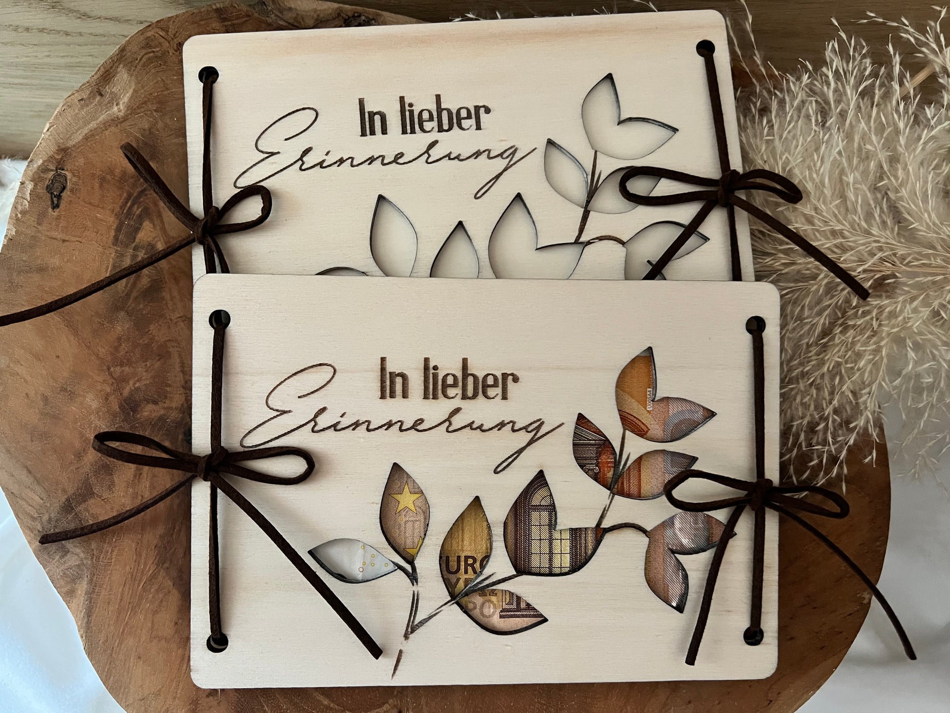 Diese Trauerkarte aus Holz ist eine wunderschöne Geste. Graviert ist es mit der Aufschrift in lieber Erinnerung. Blumenranken sind darauf ausgeschnitten, wodurch man das Geld sieht.